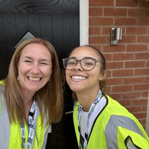 Two members of the Housing team in high-vis outside a front door