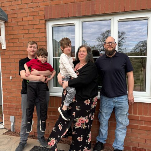Family of five people including their children, outside their new home.