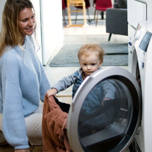 Woman and small child loading clothes into washing machine