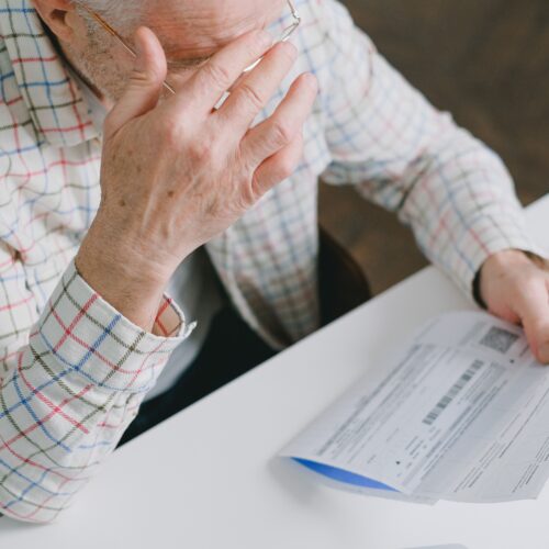 Man with head in his hands looking stressed, surrounded by bills