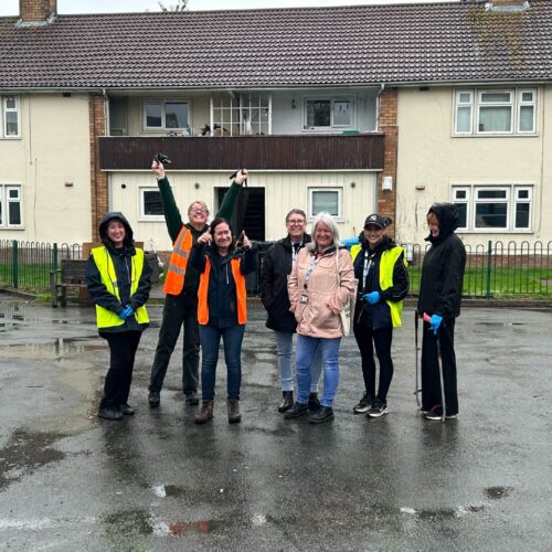 South Housing Team in front of block of flats pose for a photo in the rain